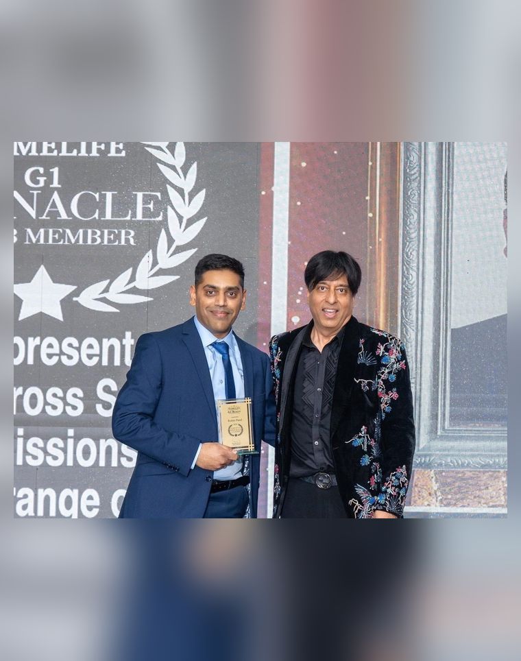 Robin Patel being handed an award, with a screen behind him reading HomeLife G1 Pinnacle Club Member.
